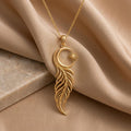 Gold Plated Silver Eclipse Feather Necklace on champagne fabric, showing an open crescent, radiant sun detail, and flowing feather pendant