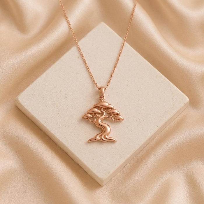 Rose Gold Plated Ficus Flow Necklace with a flowing tree pendant on a pale stone block