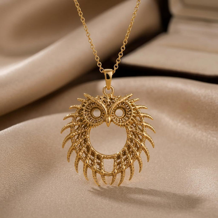 Gold Plated Silver Fossil Owl Halo pendant necklace with circular eye openings and feather-like openwork on beige satin