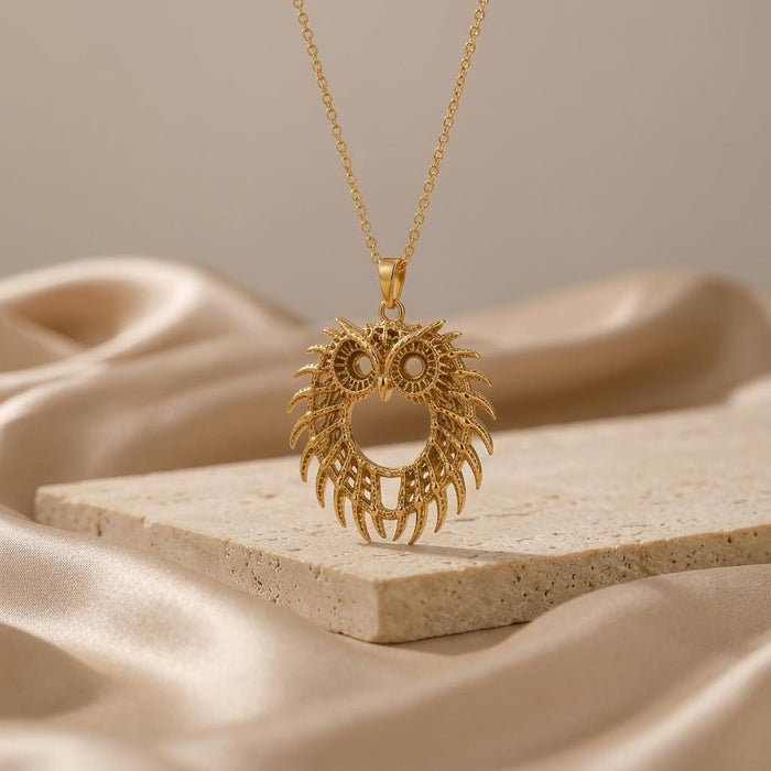 Gold Plated Silver Fossil Owl Halo pendant necklace displayed above a pale stone slab with satin folds