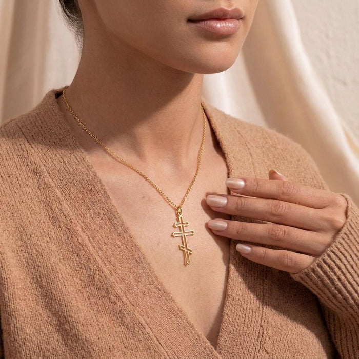 Gold Plated Silver openwork cross necklace worn with a hand beside the pendant