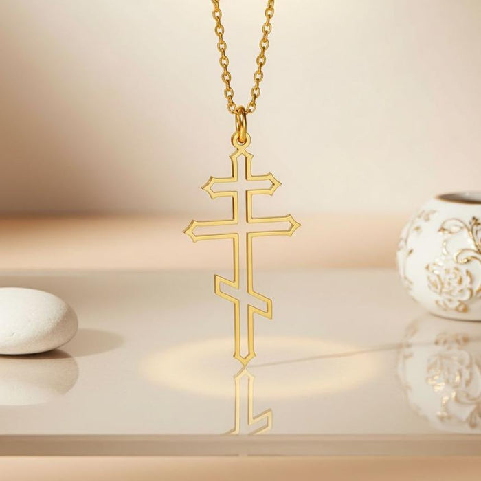 Gold Plated Silver three-bar cross pendant displayed on a reflective surface