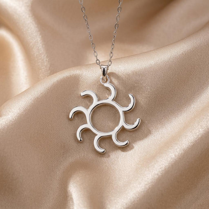 Close view of the Gold Symbol Necklace pendant with eight curved rays on champagne satin
