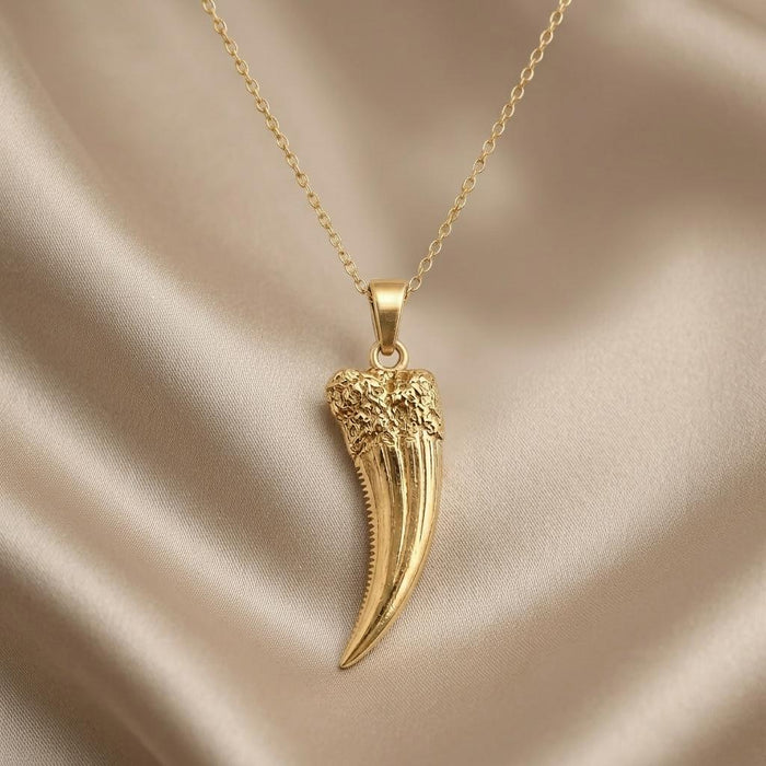 Close-up of a Gold Plated Silver Homotherium fang pendant showing the textured upper section and serrated inner edge