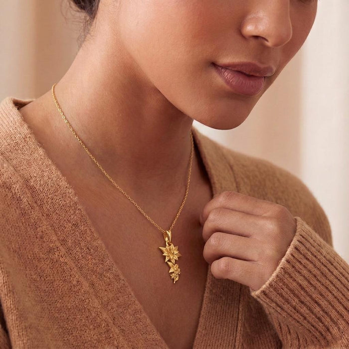 Lily Flower Necklace with a cascading floral pendant worn with a brown V-neck knit