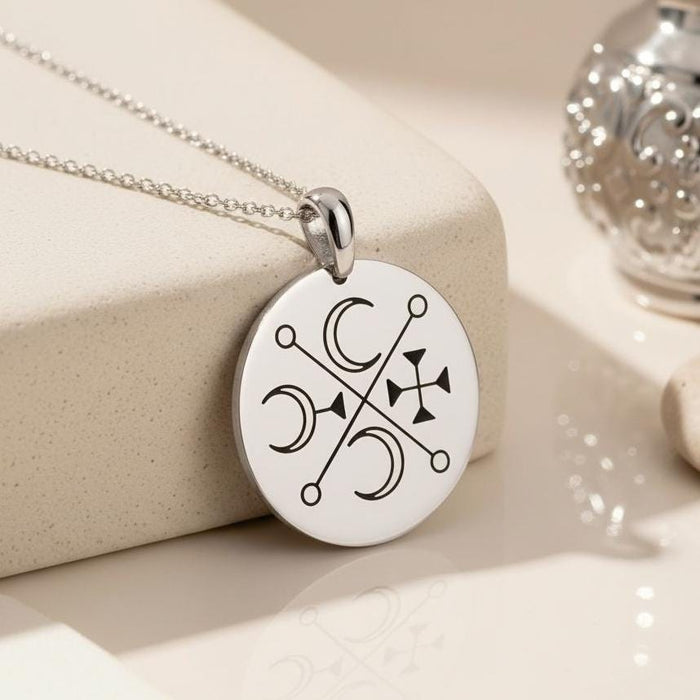 Silver Murmur Sigil Necklace close-up showing the round engraved pendant on a cream display block