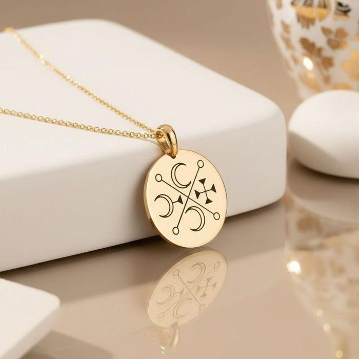 Gold Plated Silver Murmur Sigil pendant displayed beside white jewelry blocks