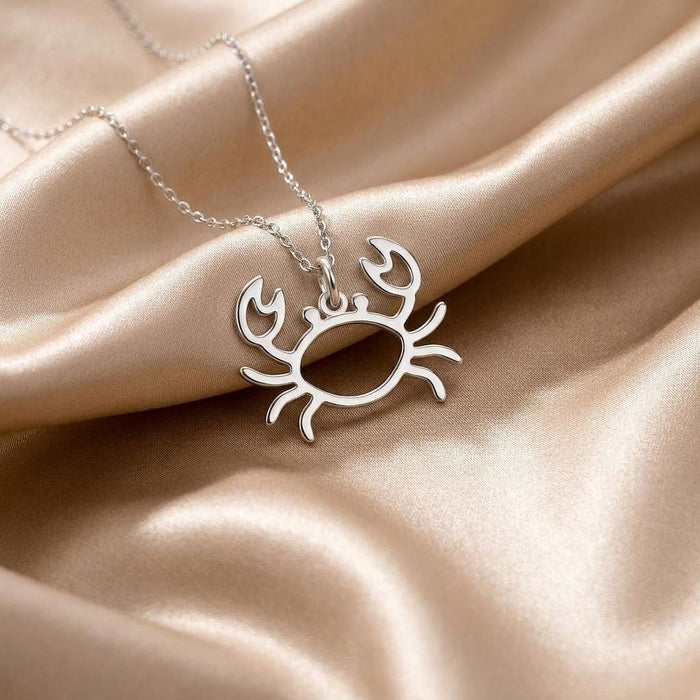 Openwork crab pendant necklace displayed on champagne satin fabric