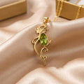 Gold Plated Silver Peridot Elf Necklace with a pointed-ear elf profile and green marquise-cut center stone on champagne satin