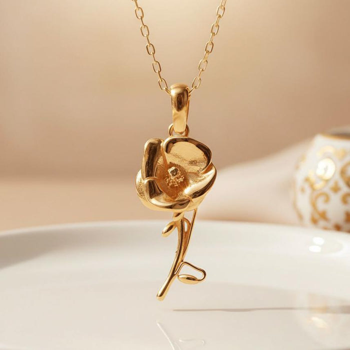 Close view of a Gold Plated Silver Poppy Flower Necklace with layered petals, raised center, curved stem, and open leaf-like detail