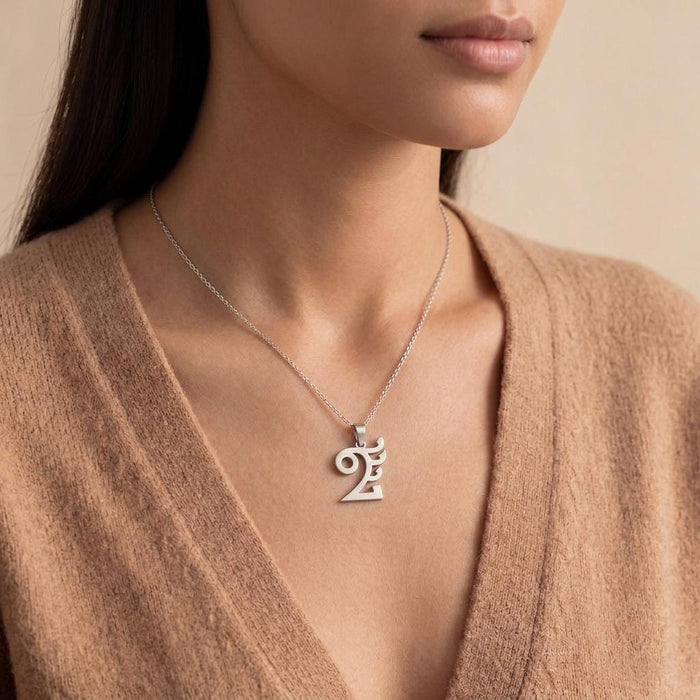 Quetzalcóatl pendant necklace worn with a brown V-neck knit top