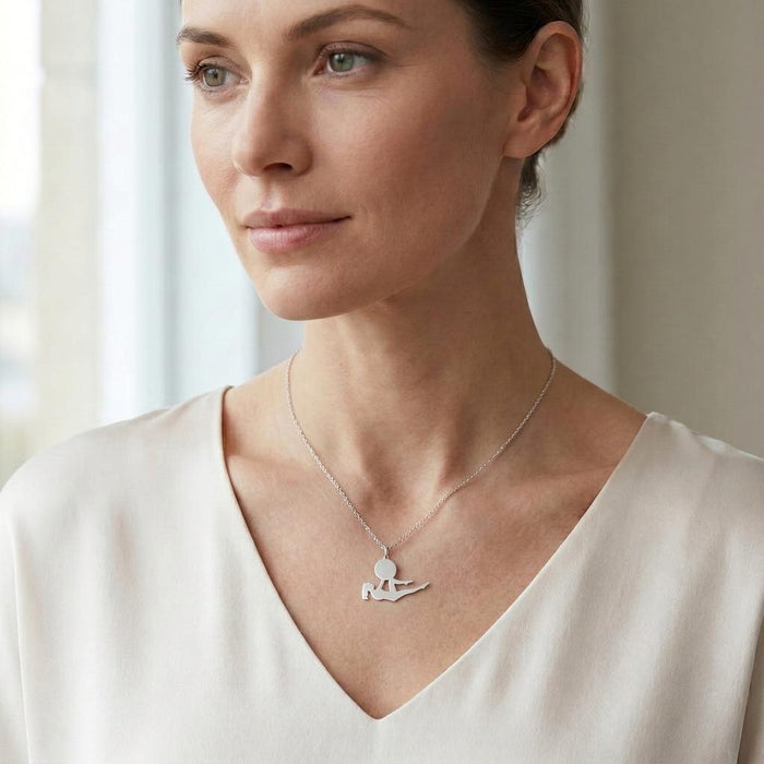 Reclining yoga pose necklace worn with a white V-neck blouse