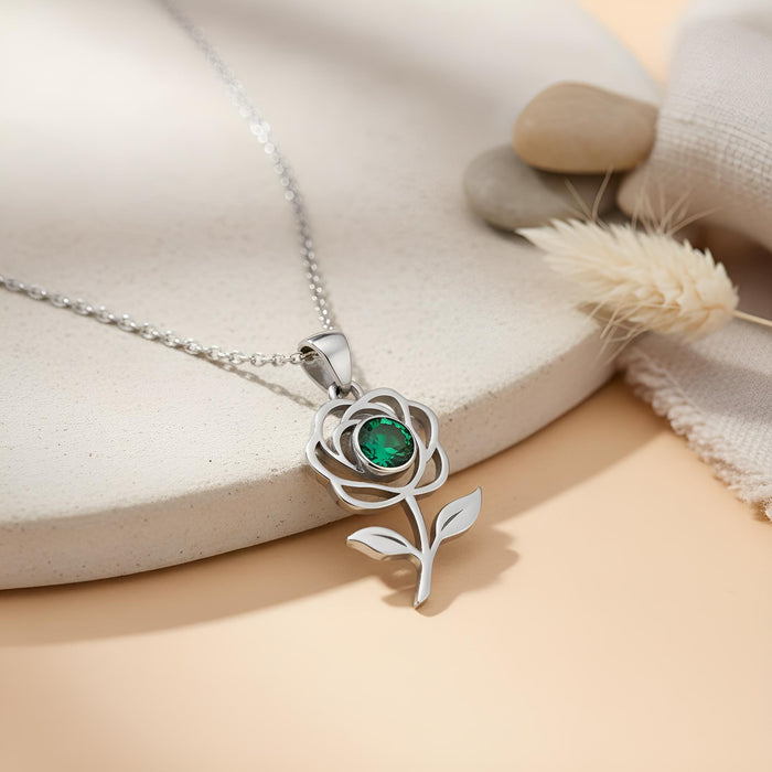 Silver Rose Flower Necklace with a green round center stone on a styled display surface