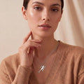 Running Woman Necklace in Silver worn with a brown V-neck sweater