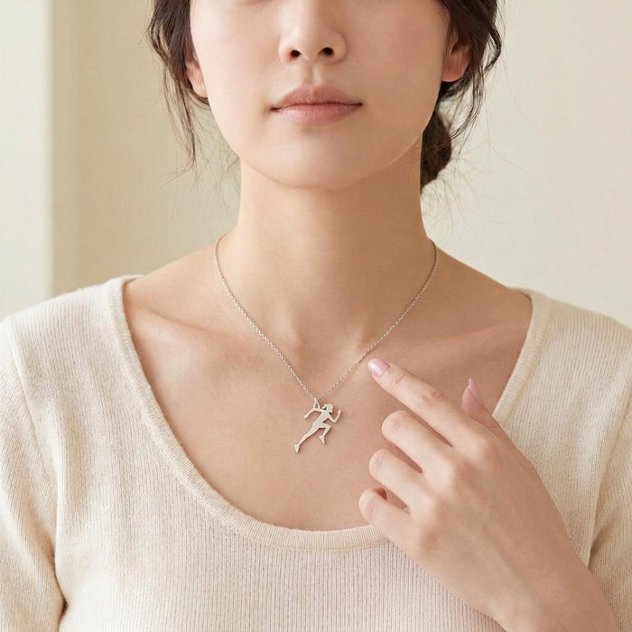 Running Woman Necklace in Silver worn at the collarbone with a cream knit top