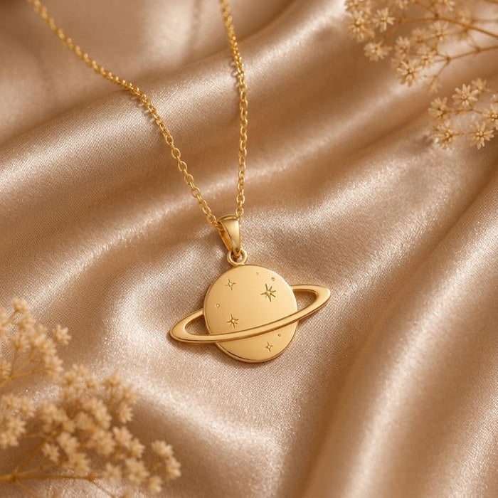 Gold Plated Silver Saturn Ring Necklace with engraved stars and an orbit ring displayed on champagne satin