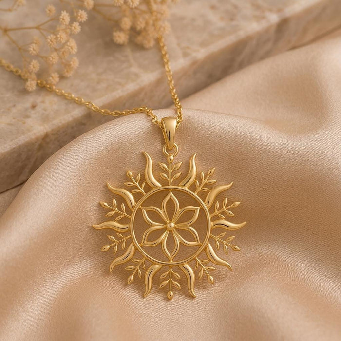 Gold Plated Silver Solstice Bloom pendant necklace with a six-petal flower, circular frame, curved rays, and leaf details on champagne satin