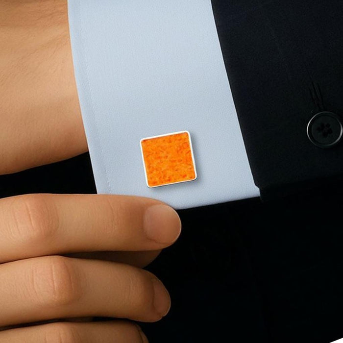 Square amber cufflink worn on the cuff of a light blue dress shirt