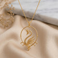 Gold Plated Silver Swan Aura Pendant with a crowned swan in an open circular frame on champagne satin