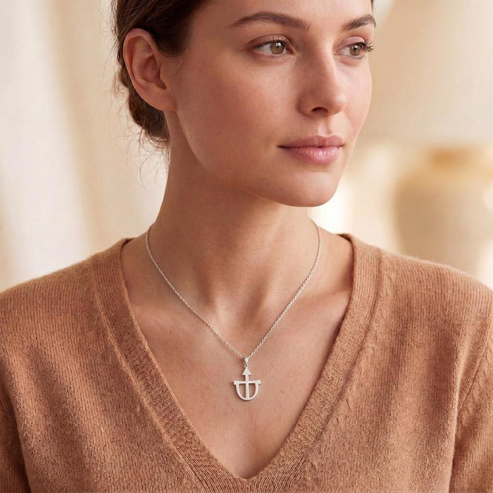 Side portrait of a model wearing the Teutonia Symbol Necklace with a V-neck knit top