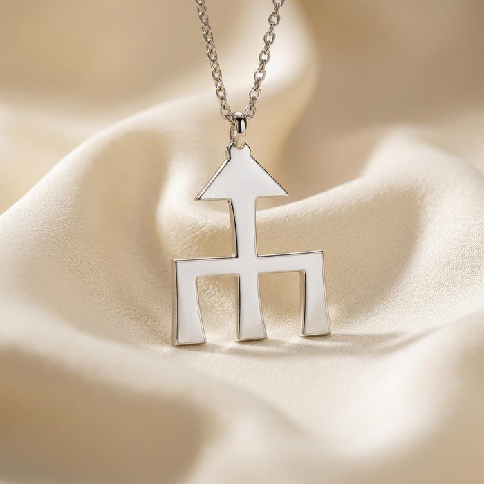 Close-up of Silver Themis symbol pendant with arrow-like top on cream satin