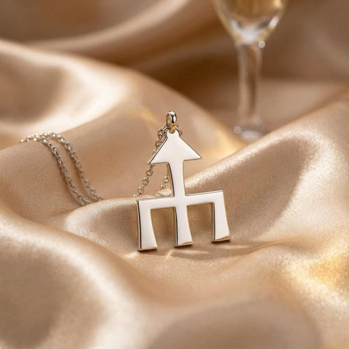 Silver Themis symbol pendant displayed on champagne-colored satin
