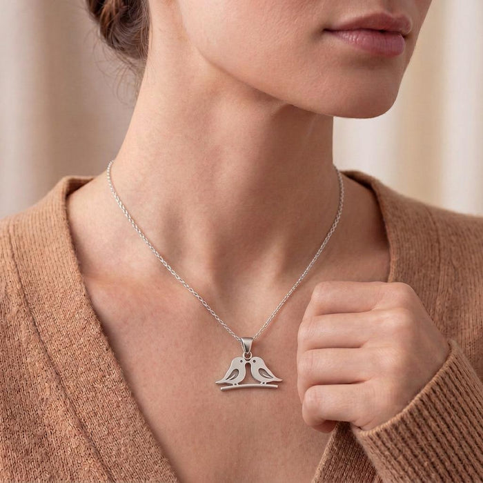 Silver Two Birds Necklace worn at the collarbone with a peach knit top