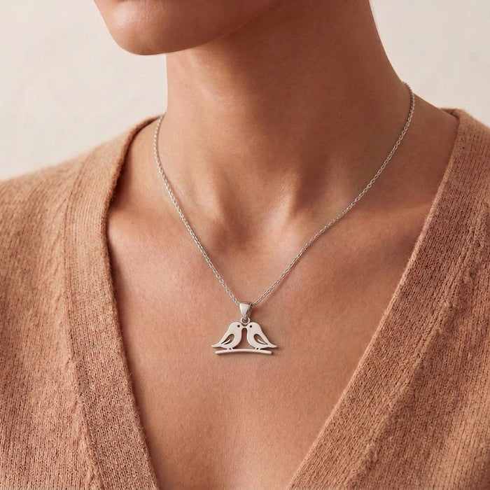 Close worn view of the Silver Two Birds Necklace against a peach knit top