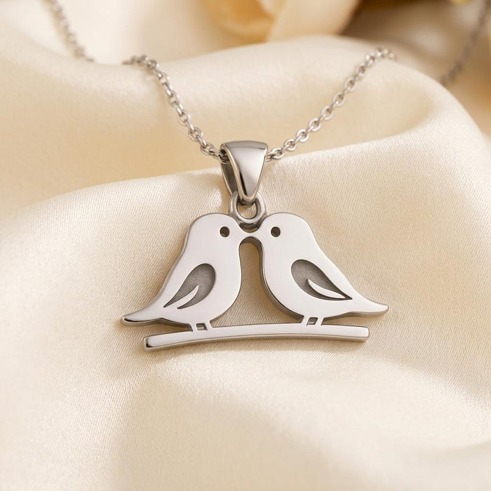 Close-up of two inward-facing bird silhouettes with wing cutouts on a curved branch pendant