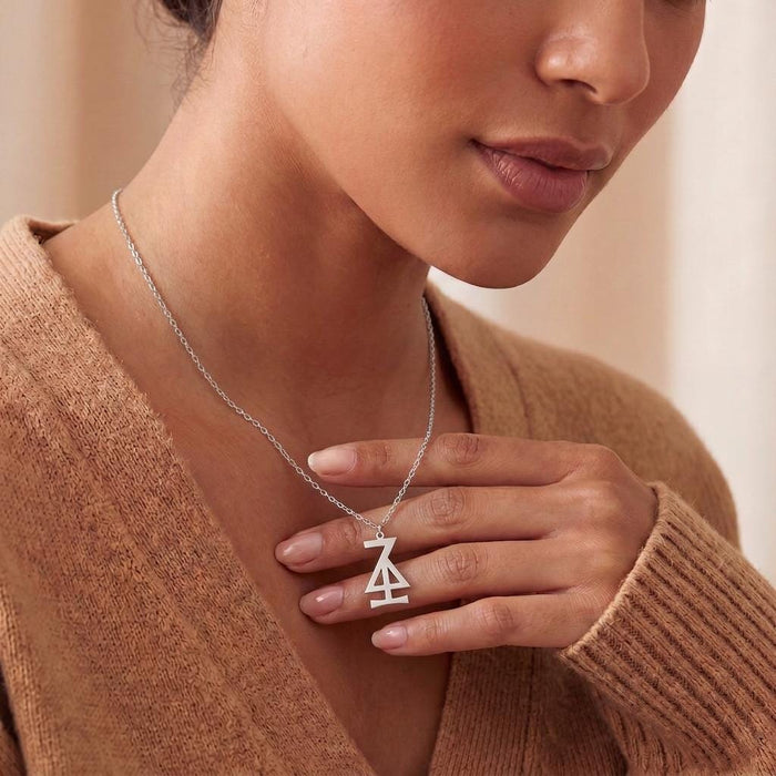 Hansa Asteroid Symbol Necklace worn with a warm brown V-neck sweater