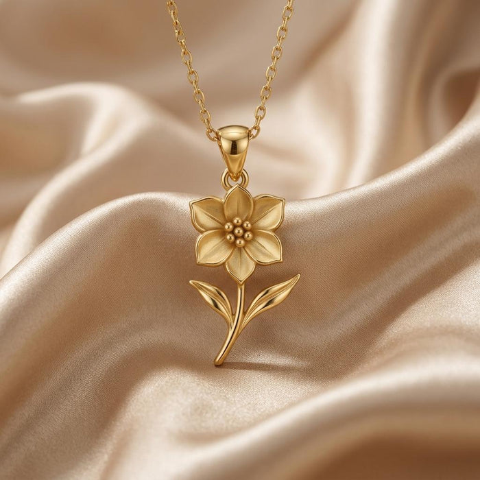 Close-up of gold-toned five-petal flower pendant on champagne satin