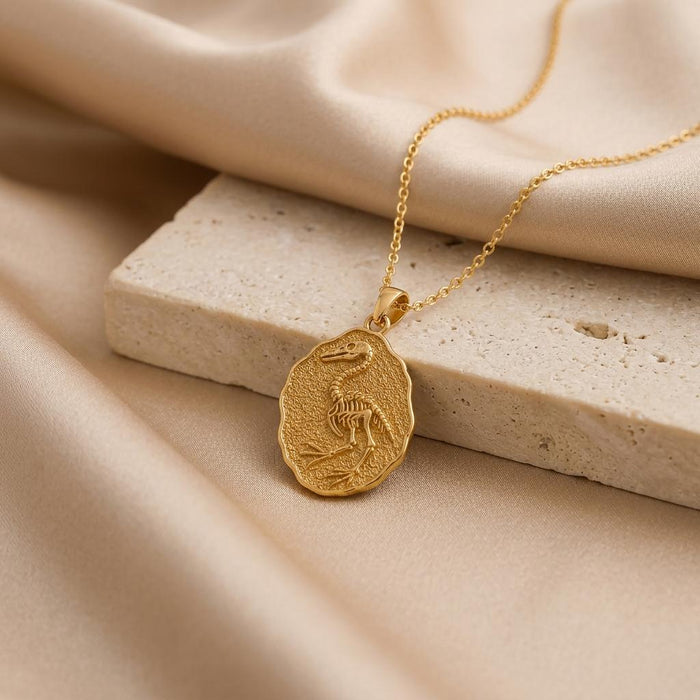 Gold Plated Silver Hesperornis Fossil Pendant beside a pale stone block on champagne satin