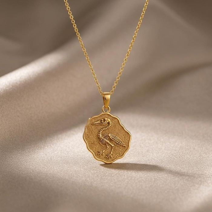 Gold Plated Silver Ichthyornis fossil pendant necklace with raised bird skeleton on draped neutral fabric