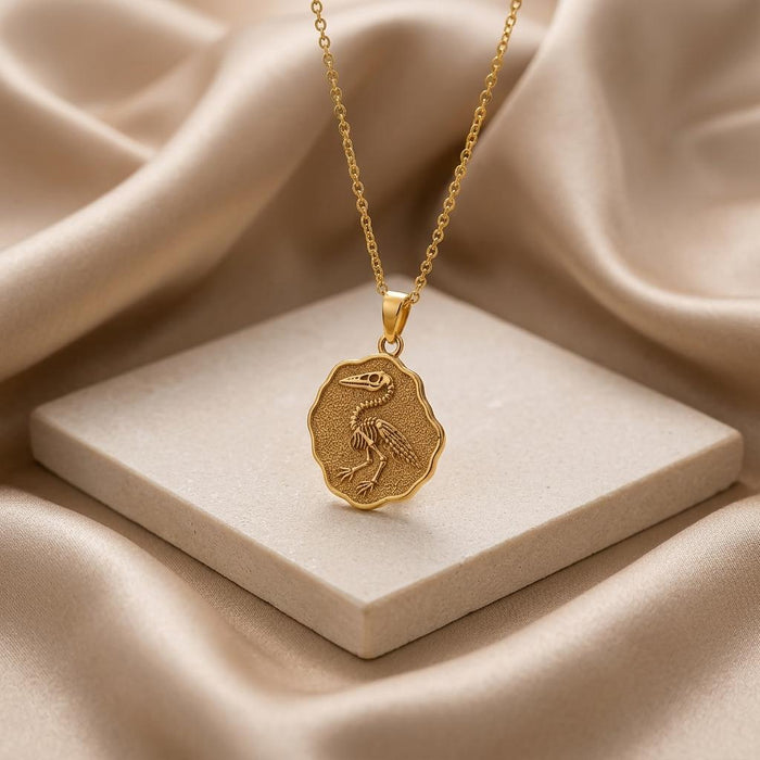 Gold Plated Silver Ichthyornis fossil medallion necklace displayed on a cream stone tile