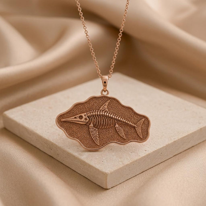 Rose Gold Plated Ichthyosaurus fossil plaque pendant displayed on a square stone block