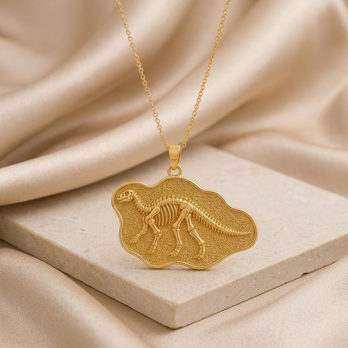 Gold Plated Silver Iguanodon skeleton plaque pendant on cream satin and a pale stone block