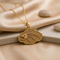 Gold-finish Leedsichthys Fossil Pendant Necklace with a fish skeleton relief on champagne satin beside smooth stones