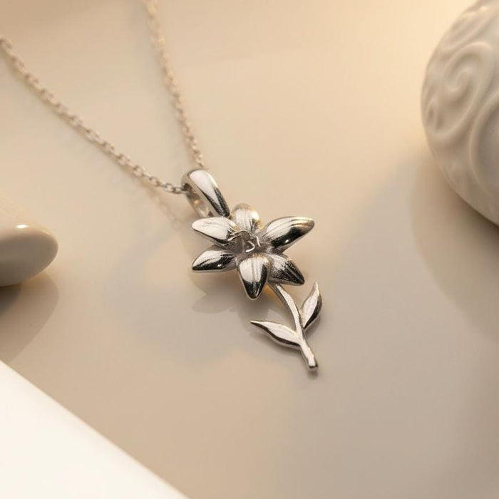 Close-up of the Silver Lily Flower Necklace showing sculpted petals, curved stem, and two leaves