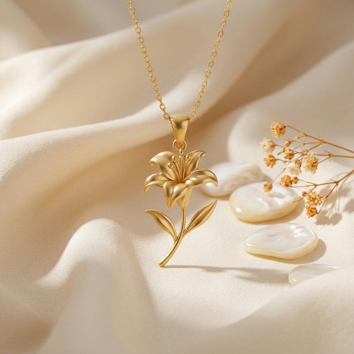 Gold Plated Silver lily flower pendant necklace with a sculpted bloom on ivory fabric beside shells and dried flowers