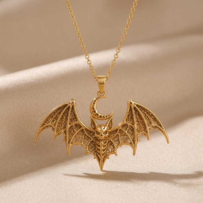 Gold-toned Lunar Bat Relic pendant necklace suspended above champagne satin