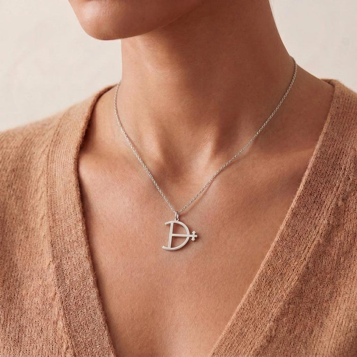 Magnesium Symbol Necklace worn at the collarbone with a textured neutral knit top
