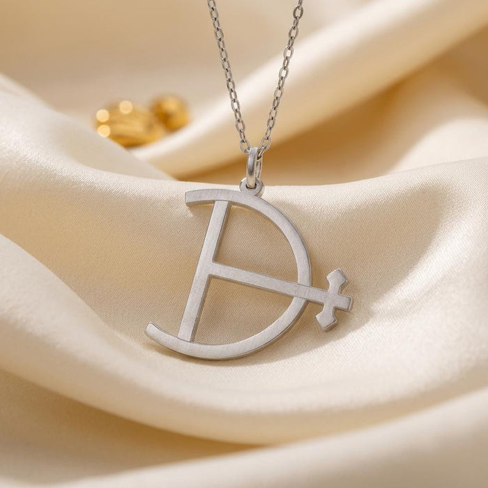 Detailed view of the openwork Magnesium Symbol Necklace pendant and chain on ivory satin