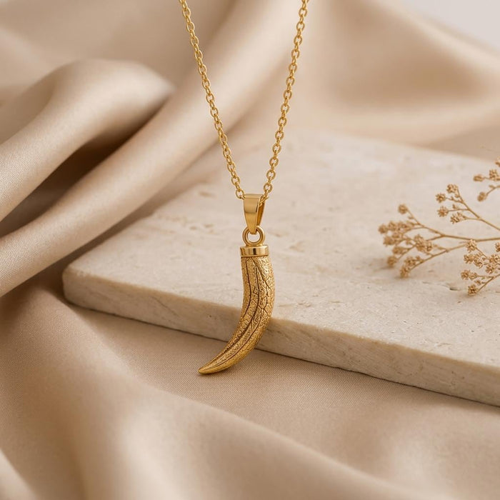 Gold Plated Silver textured curved mammoth tusk pendant hanging above a pale stone block