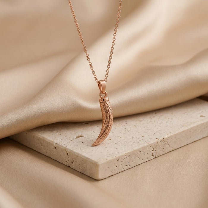Rose Gold Plated Mammoth Tusk Fossil Pendant Necklace on a pale stone display
