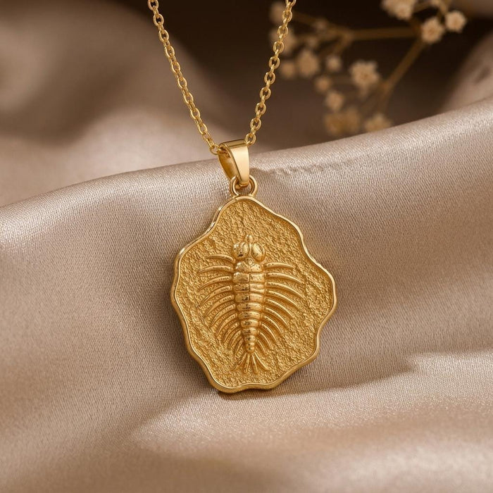 Gold Plated Silver Marella fossil pendant with raised trilobite relief on champagne satin