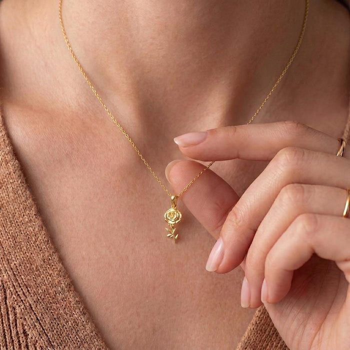 Gold Plated Silver floral necklace worn at the collarbone with a hand near the pendant