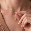 Gold Plated Silver floral necklace worn at the collarbone with a hand near the pendant