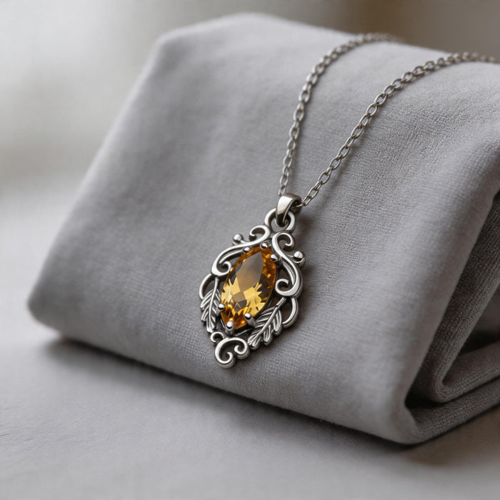 Silver-finish Marquise Yellow Topaz Necklace with an ornate yellow marquise pendant draped over a folded gray cushion