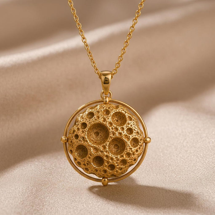 Gold Plated Silver Mathilde Asteroid Pendant Necklace with a crater-textured sphere inside a circular orbit frame on champagne satin