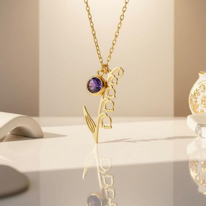 Gold Plated Silver May Birth Flower Necklace with bell-shaped blooms and a round purple stone on a reflective tabletop